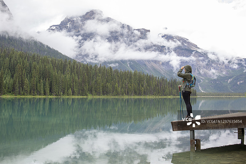 暴风雨天，徒步女性站在高山湖泊的码头尽头图片素材