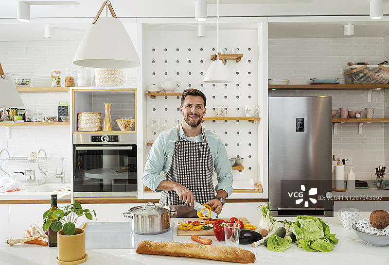 在厨房里看着镜头微笑做饭的男人图片素材