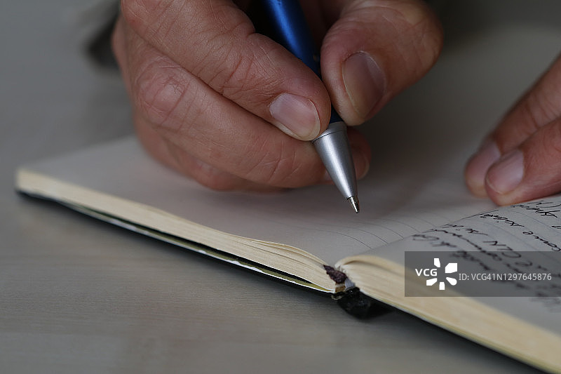 男人用圆珠笔在笔记本上书写图片素材