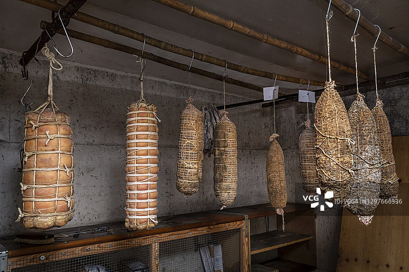 在乡村地窖中悬挂风干的手工萨拉米香肠和培根卷图片素材