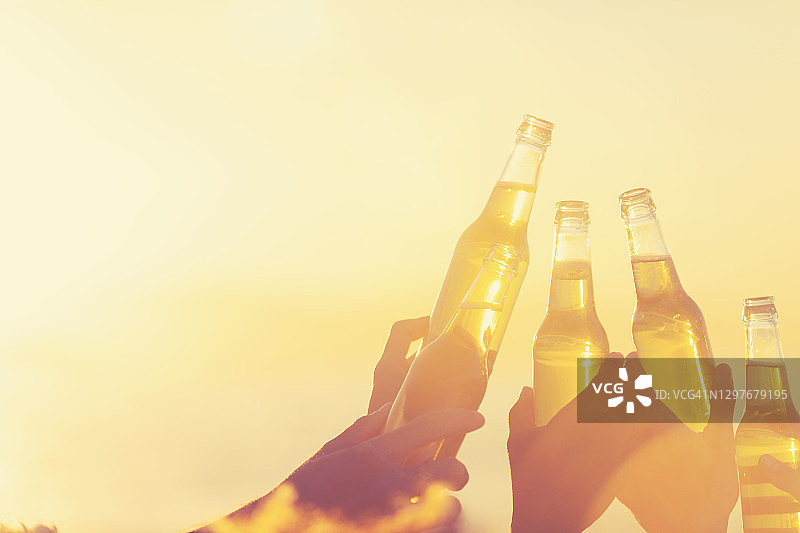 一群年轻人在日落时分的沙滩上聚会图片素材