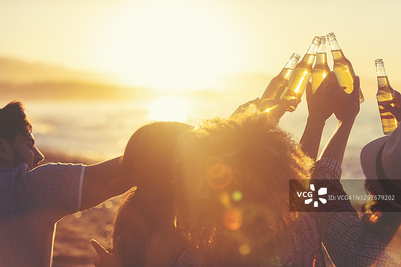 一群年轻人在日落时分的沙滩上聚会图片素材