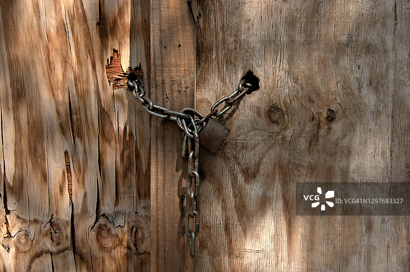 风化胶合板门上的挂锁和链条图片素材