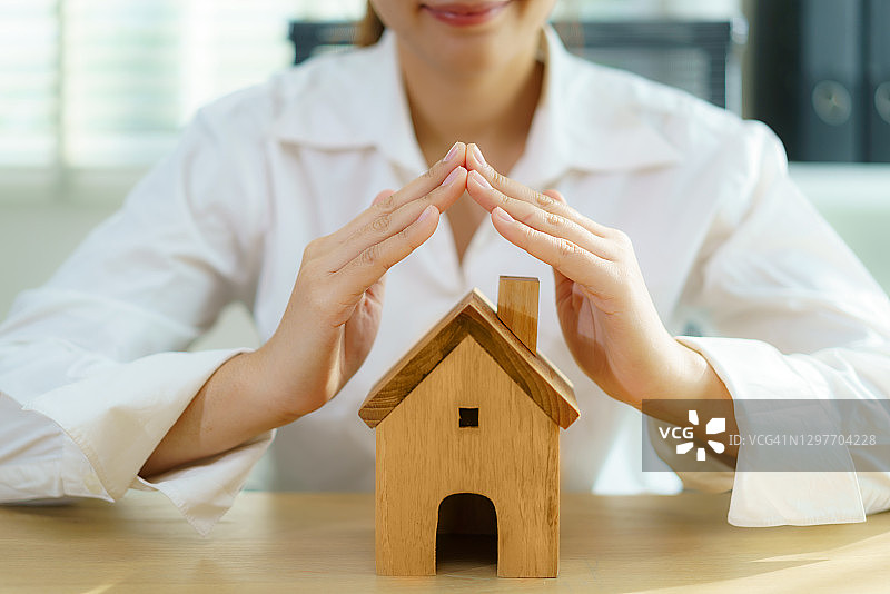 保护性商业女性之手呵护房屋，房屋和房地产保险概念图片素材