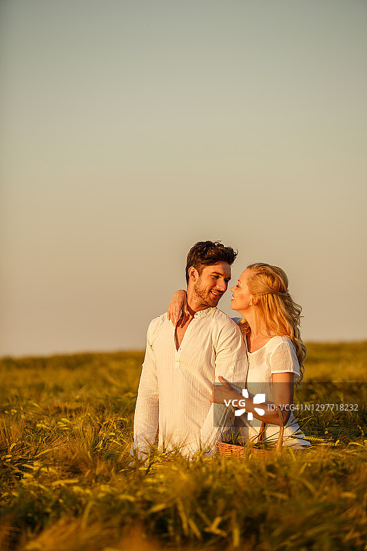 充满爱意的夫妇在日落时分的大田里收割小麦图片素材