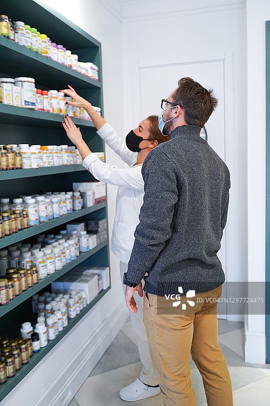 药剂师帮助顾客选择膳食补充剂图片素材