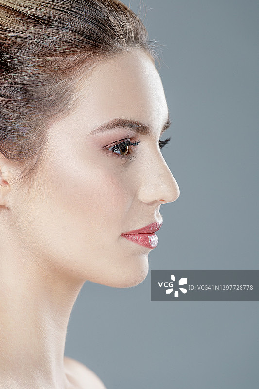 在灰色背景下摆姿势的漂亮金发年轻女子无上装侧面照图片素材