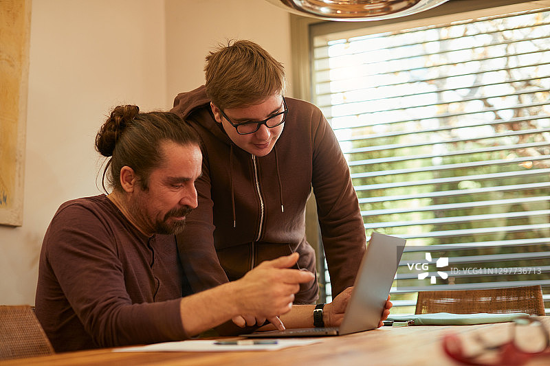 少年帮助父亲解决电脑问题图片素材