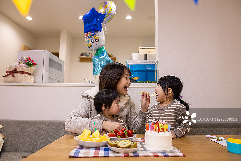 年轻母亲在生日派对上喂女儿图片素材