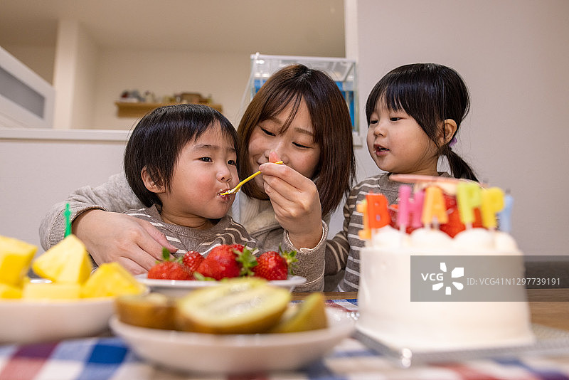 年轻母亲在宝宝一周岁生日时喂奶图片素材
