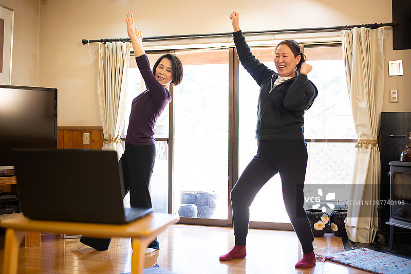 母女在家通过笔记本电脑在线锻炼图片素材