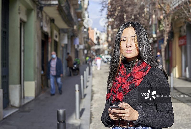 年轻女子在城市街道上使用手机图片素材