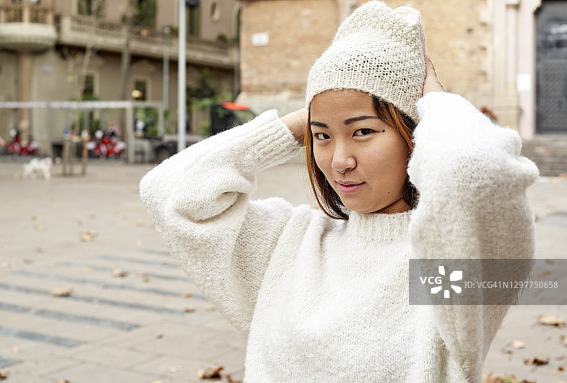 戴着针织帽站在城市街道上的漂亮女人图片素材