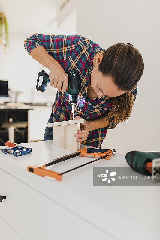 女人居家工作使用电动螺丝刀拧螺丝图片素材