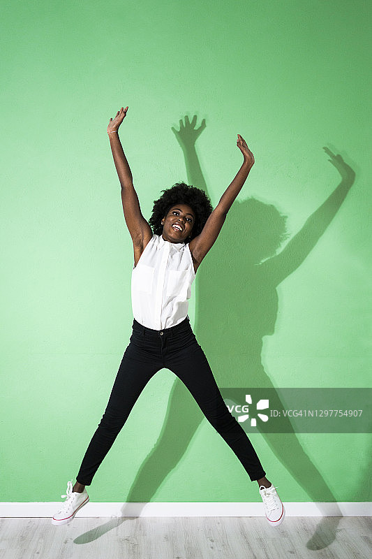在绿色背景下跳跃的年轻女人图片素材