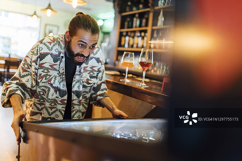 在酒吧玩弹珠游戏的快乐络腮胡男人图片素材