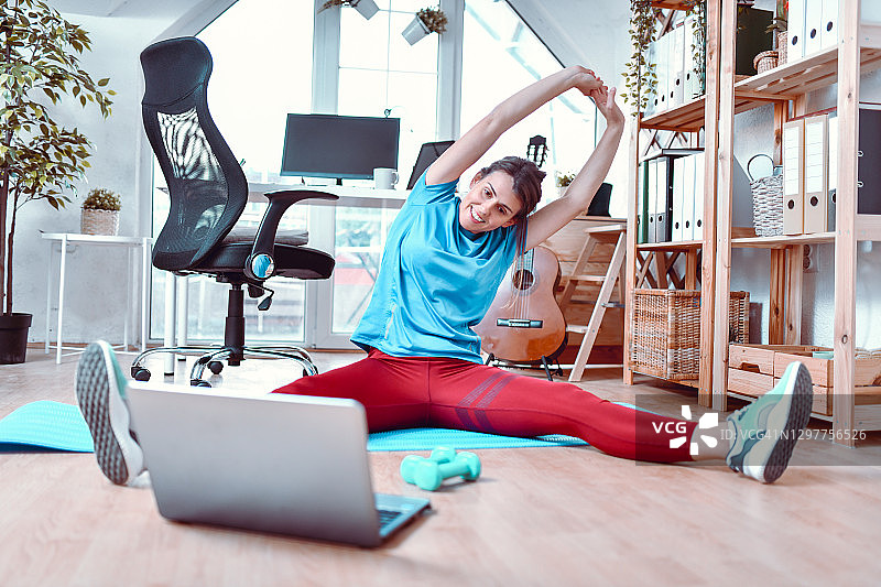 运动型女人使用笔记本电脑进行办公室健身视频课程图片素材