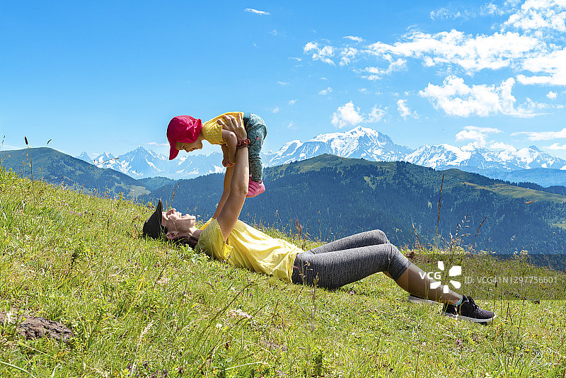 母亲在阿拉维山坳的草地上抱起女婴，法国上萨瓦省图片素材