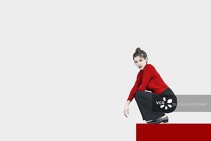 蹲在白色背景前的年轻漂亮女子肖像图片素材