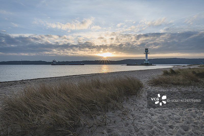 德国石勒苏益格-荷尔斯泰因州腓特烈斯奥尔特日出时的海滩和灯塔图片素材