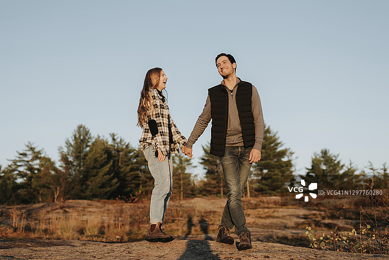 秋季徒步旅行中手牵手的年轻情侣图片素材