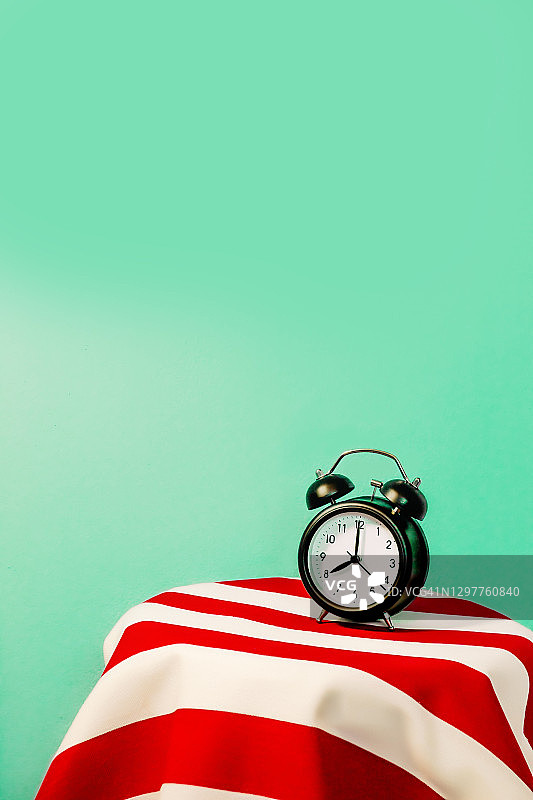 闹钟在红白条纹图案上的工作室照片图片素材
