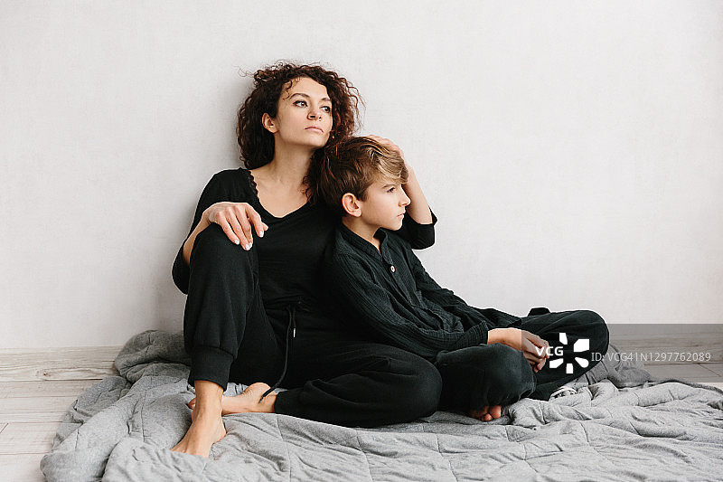 漂亮的女人和她的青少年儿子坐在灰色背景上微笑图片素材