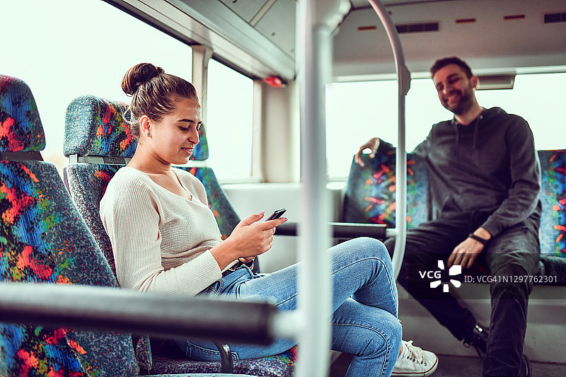 女人和她的朋友在公共汽车上旅行时使用智能手机图片素材