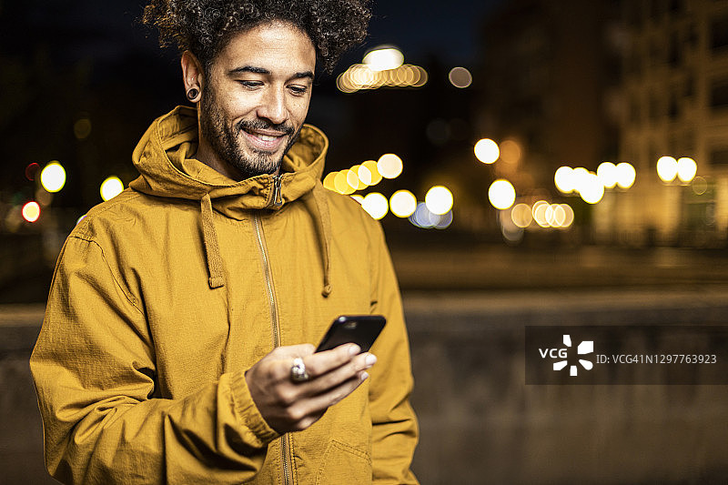 穿着连帽衫在户外使用手机的男人图片素材