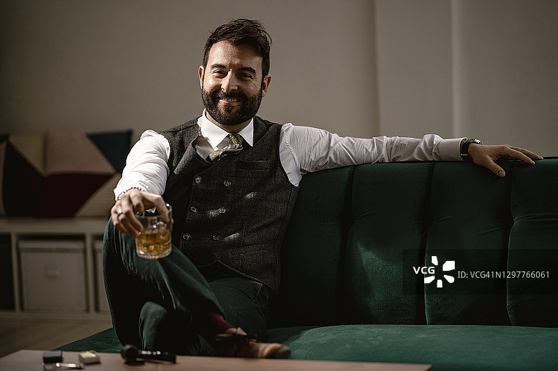 坐在沙发上手持威士忌酒杯的胡须男士肖像图片素材