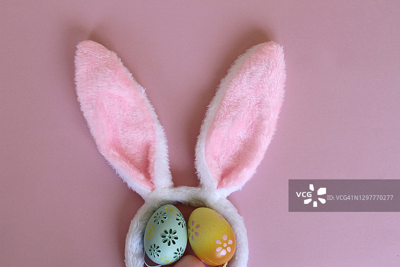 粉色背景上的复活节彩蛋和兔子耳朵图片素材