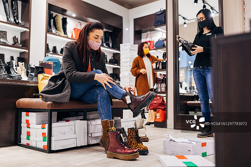 一位快乐的女士在现代鞋店试穿不同款式的靴子图片素材