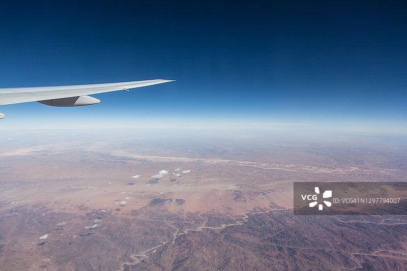 飞机飞越沙漠，透过舷窗看到的机翼图片素材