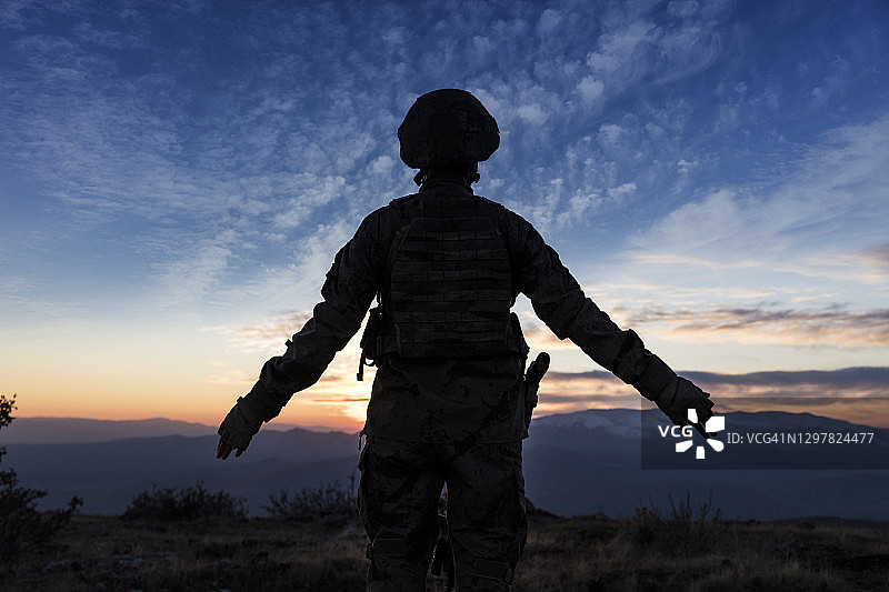 战场上，女兵在夕阳下站立的剪影图片素材