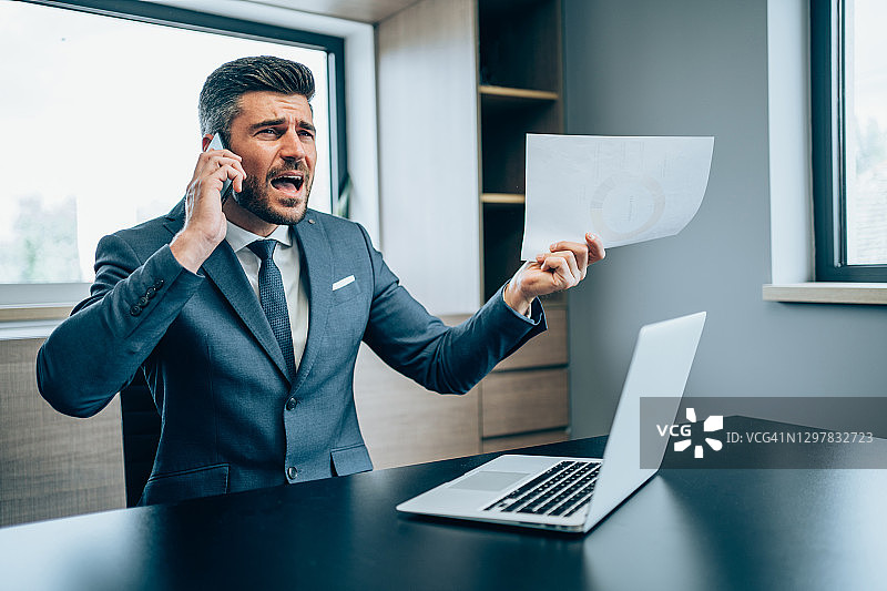 生气的商人在办公室用手机通话图片素材