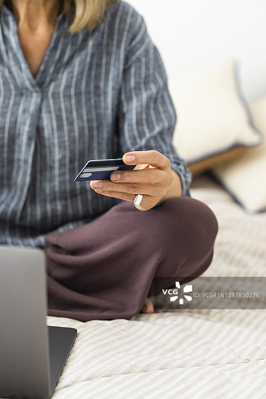 网上购物:一个匿名妇女使用信用卡支付她的网上订单，一个近距离图片素材