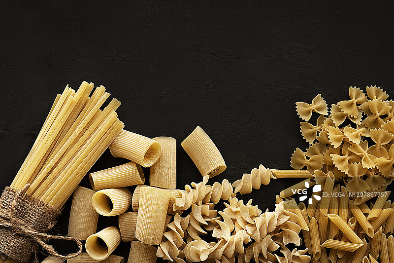 深色背景上的不同类型的干意面图片素材