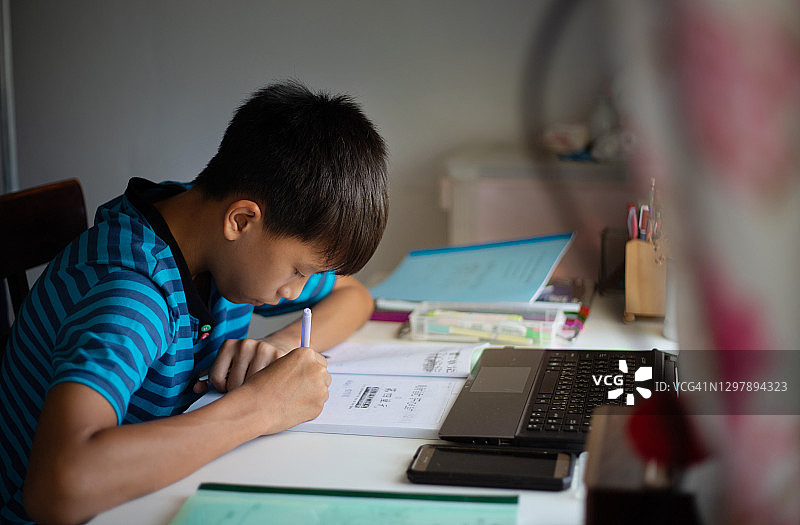 在家通过笔记本电脑在线学习的亚洲年轻男学生图片素材