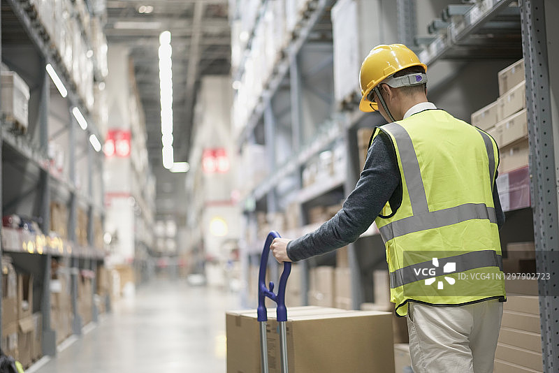 戴安全帽的工人在仓库中搬运货物图片素材
