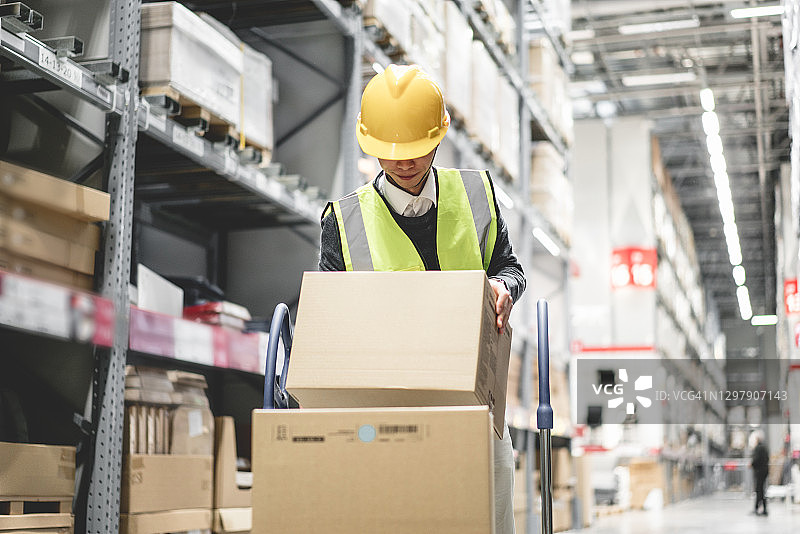 戴安全帽的工人在仓库中搬运货物图片素材
