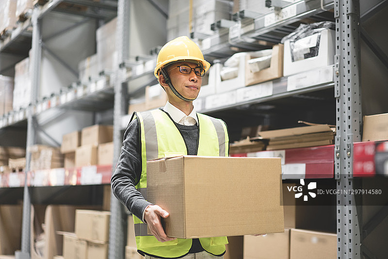 戴安全帽的工人在仓库中搬运货物图片素材