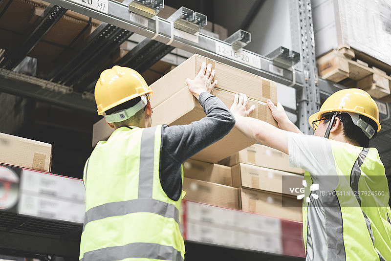 戴安全帽的工人在仓库中搬运货物图片素材