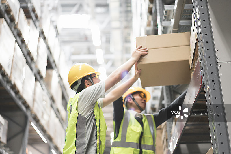 戴安全帽的工人在仓库中搬运货物图片素材