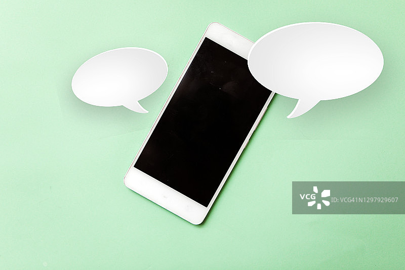 蓝色背景上的智能手机与纸质对话气泡，交流概念图片素材