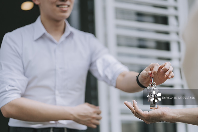 华人房地产经纪人在新房将房屋钥匙交给房主图片素材