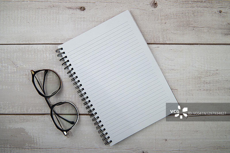 木桌上的空白记事本和眼镜图片素材