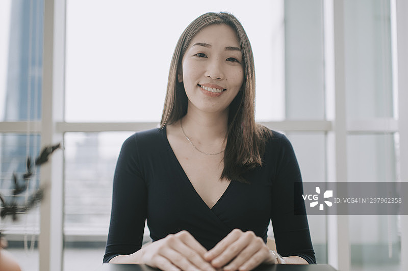 亚洲华人美女在室内看着摄像头进行视频通话微笑图片素材