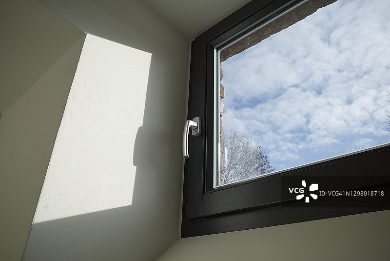 关闭的黑白百叶窗的内部视图和特写细节，背景是晴朗的蓝天和白云。图片素材