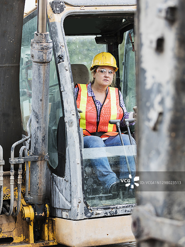 驾驶推土机的西班牙裔女建筑工人图片素材