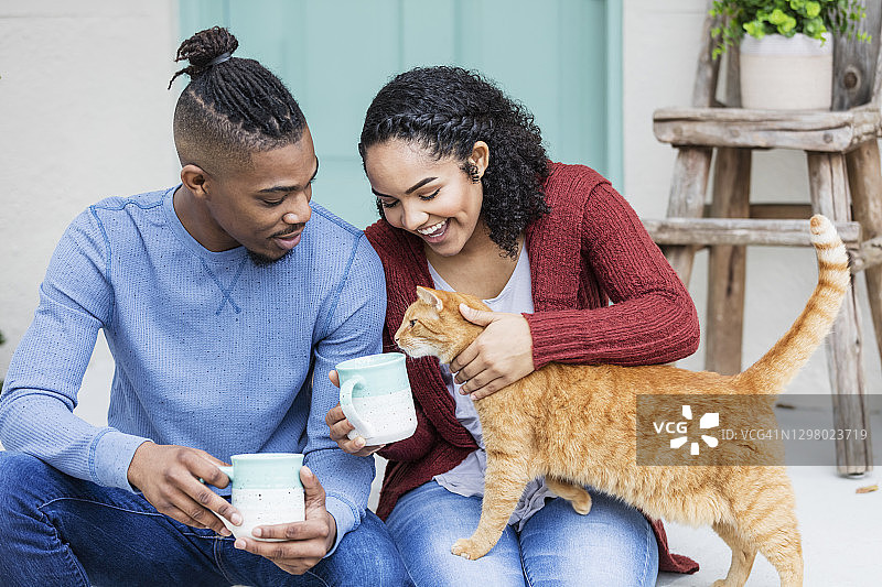 非裔美国夫妇在门廊台阶上爱抚猫图片素材